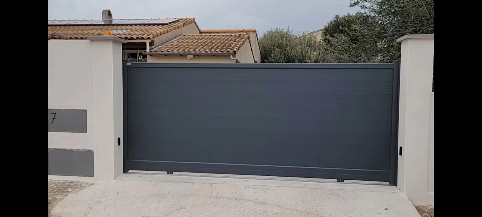 Portail coulissant en aluminium anthracite posé devant une villa