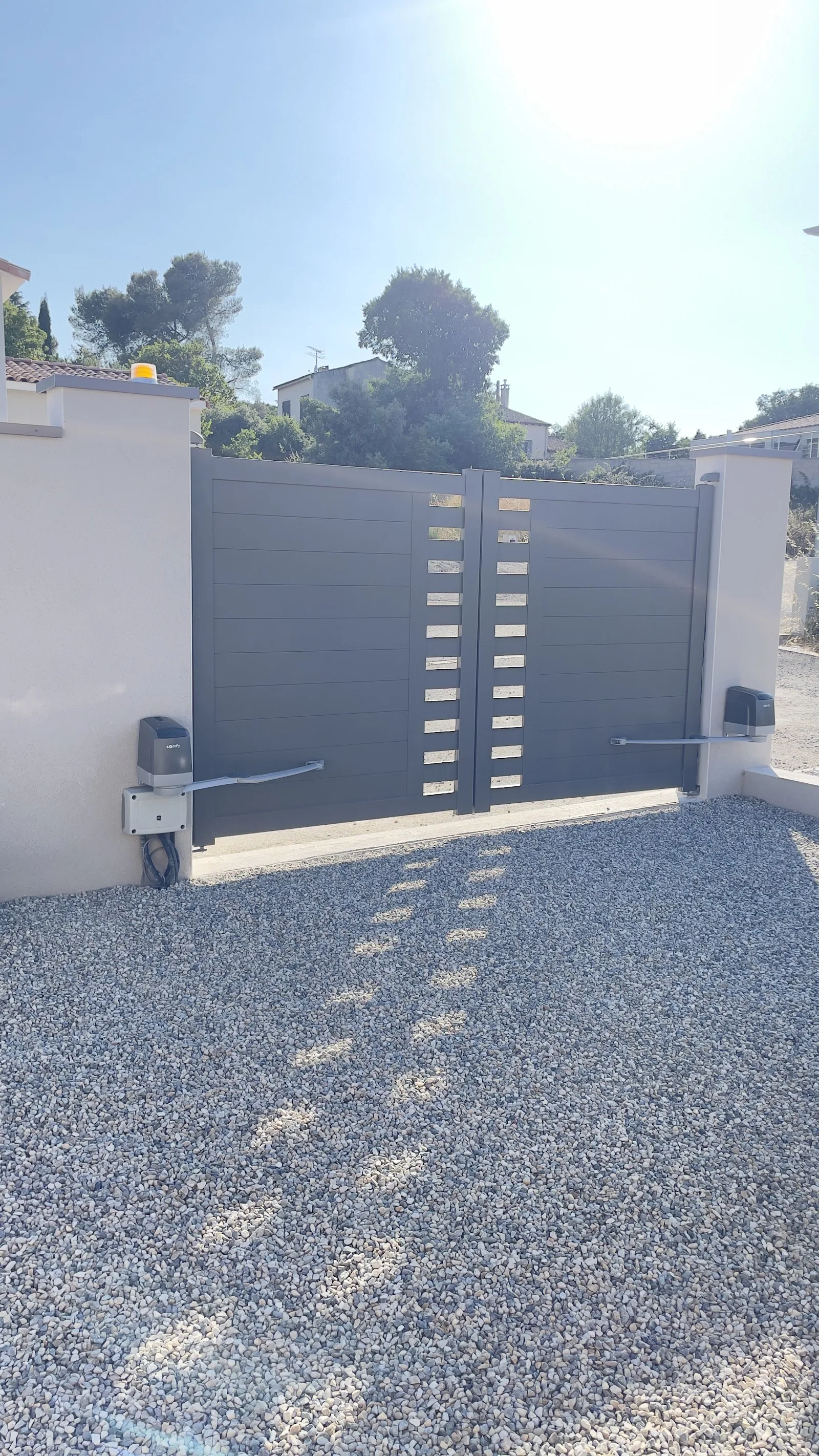 Portail battant en aluminium anthracite, motorisé, sur une entrée gravillonnée